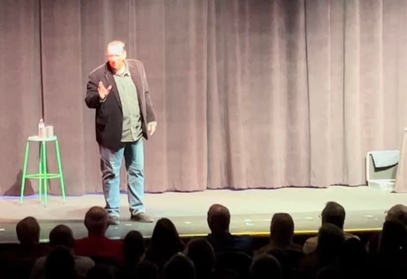 Eric Thompson commands the stage with his signature blend of comedy and charisma, working his magic on an engaged audience at what appears to be a theater or performance venue.