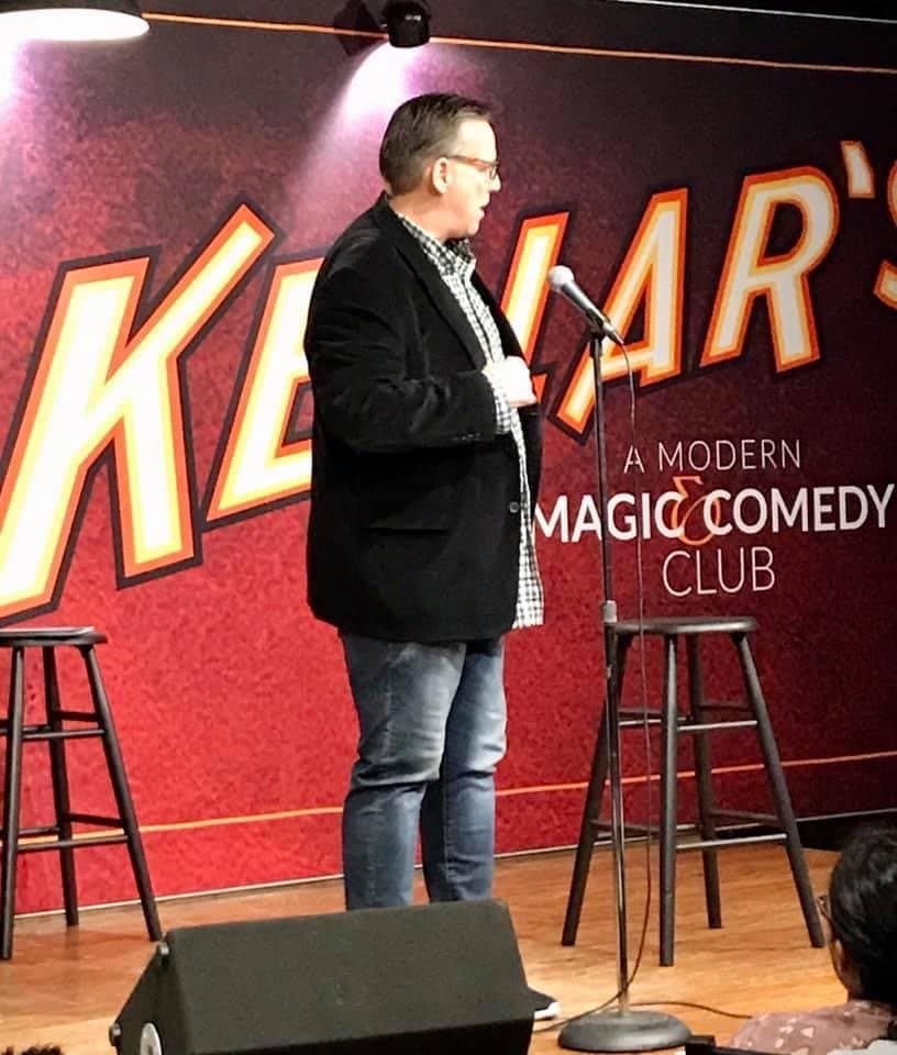 Eric Thompson takes the stage at a modern comedy club, ready to blend his signature mix of magic and humor for an intimate crowd.