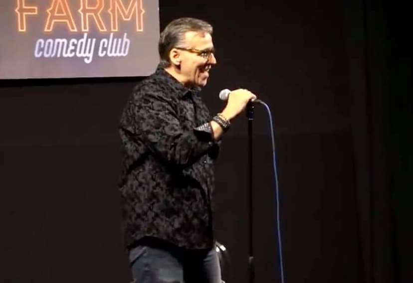 Eric Thompson delivers his signature blend of comedy and magic to an enthusiastic crowd at what appears to be a lively comedy club performance, microphone in hand and clearly in his element.