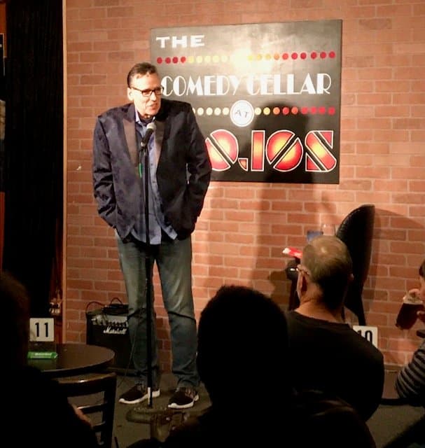 Eric Thompson takes the stage at The Comedy Cellar, working his magic with the intimate crowd in this classic brick-walled comedy club setting.