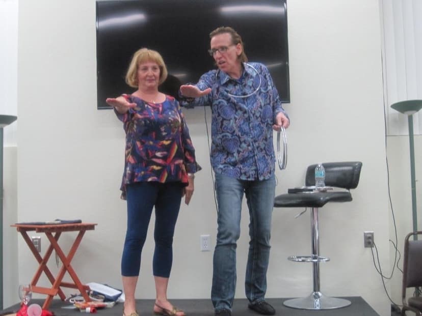 Eric Thompson brings an audience member on stage for what looks like an engaging magic demonstration, both performers clearly having a great time with the interactive routine.