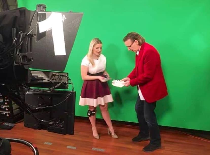 Eric Thompson works his magic in front of the cameras during what appears to be a television or video production, demonstrating a trick to his assistant against the bright green screen backdrop.