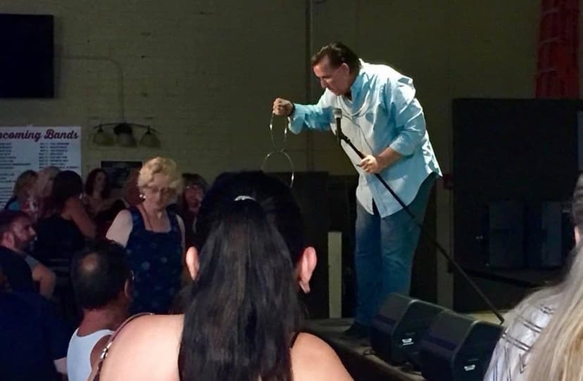Eric Thompson captivates the crowd from the stage, microphone in hand as he delivers his signature blend of comedy and magic to a packed audience.
