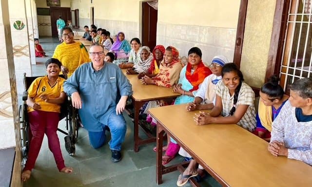 Eric Thompson brings smiles and laughter to a classroom full of enthusiastic students during what appears to be a special educational visit or community outreach performance.