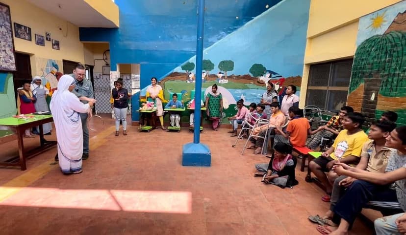 Eric Thompson captivates a young audience at what appears to be a community center or school event, with colorful murals providing the perfect backdrop for his engaging performance.