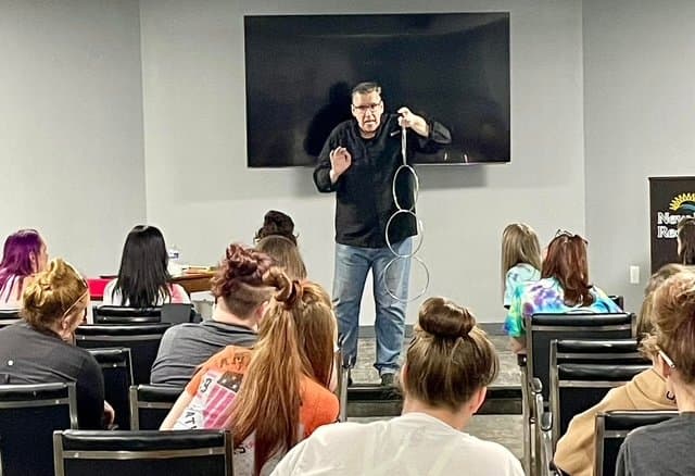 Eric Thompson captivates a classroom full of engaged students, demonstrating his magical prowess with rings while working his comedic charm on the young audience.