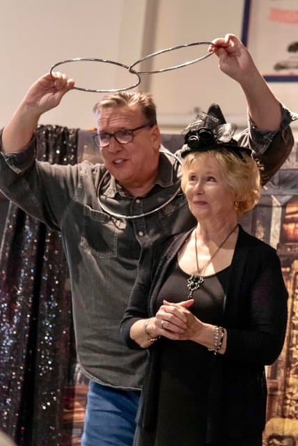 Eric Thompson demonstrates a classic linking rings illusion with a delighted volunteer, showcasing the interactive magic that has made him a favorite at events nationwide for decades.