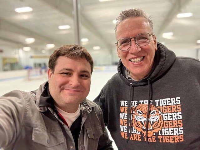 Eric Thompson shares a friendly moment with a fan at what appears to be an ice rink, showing his warm connection with audiences extends well beyond the stage.