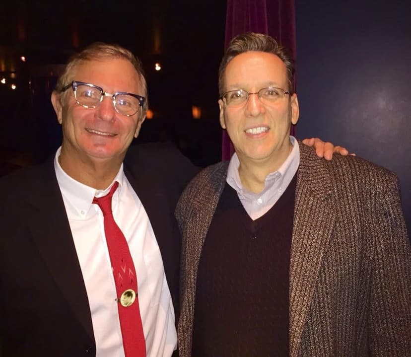 Eric Thompson shares a warm moment with a fellow entertainer, both grinning ear to ear in what looks like a classic backstage meet-and-greet after a show. The comedic chemistry between these two performers is evident even in this candid snapshot.