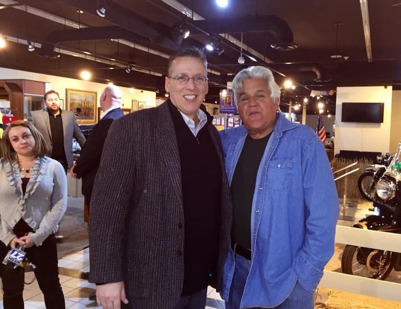 Eric Thompson shares a warm moment with a fan at what appears to be a corporate event or fundraiser, showcasing the personal connections he builds with his audiences.