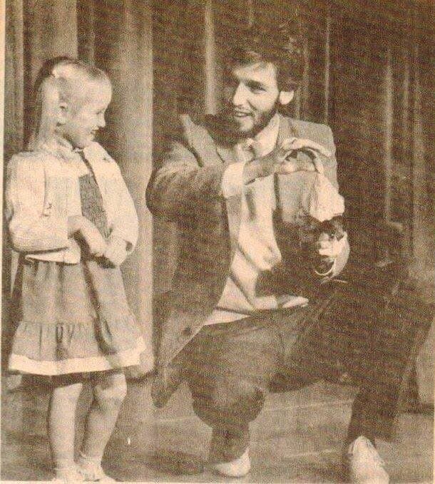Eric Thompson charms a young audience member during what appears to be an intimate performance, showcasing the warm, personal connection that has made him a beloved entertainer for decades.