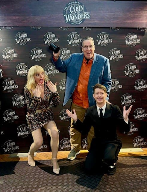 Eric Thompson strikes a playful pose with fellow performers at what appears to be a 'Cabin Wonders' themed event, showing off his natural showmanship even when he's not on stage.