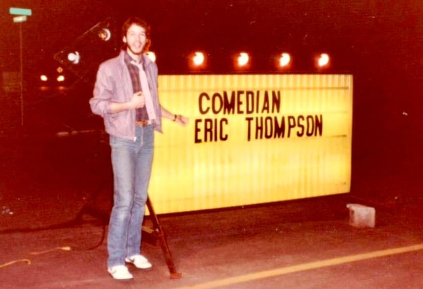 Eric Thompson takes the stage at what appears to be a comedy club or entertainment venue, with the classic marquee-style sign proudly displaying his name and comedic credentials behind him.