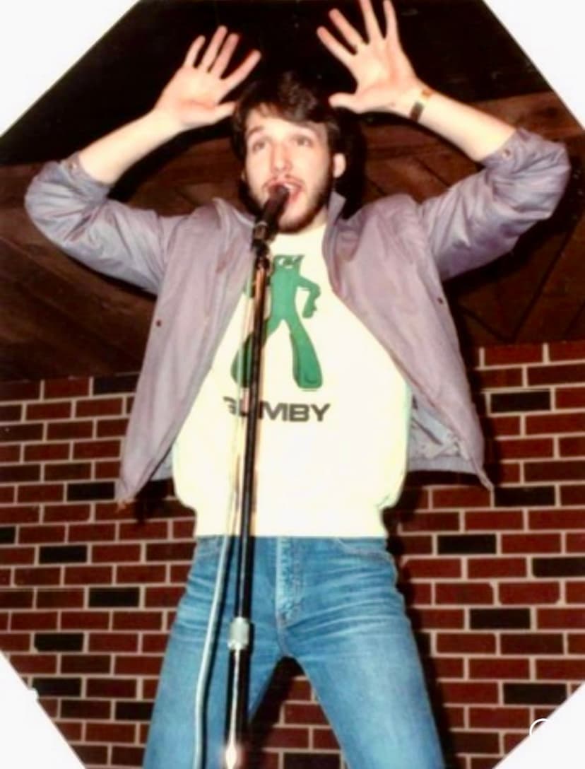 Eric Thompson brings his signature energy to the stage, throwing his hands up in theatrical style while delivering what's surely a hilarious punchline to the delighted audience.