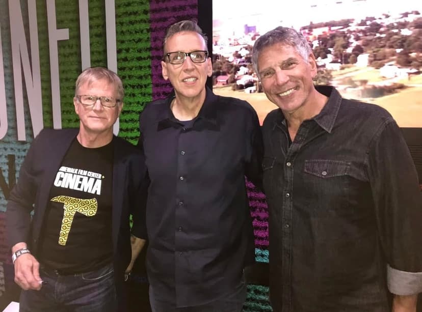 Eric Thompson shares a friendly moment with fellow entertainers at what appears to be an industry event or film center gathering, showing the camaraderie that exists in the comedy and entertainment world.