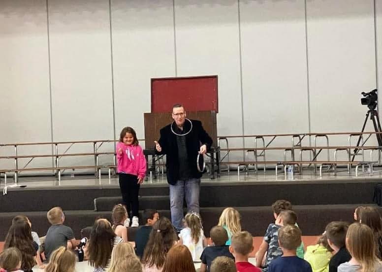 Eric Thompson captivates a young audience from the stage, with a little volunteer in pink joining him for what's sure to be a memorable moment of magic and laughter.