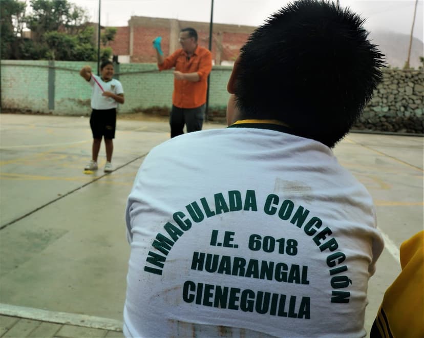 Eric Thompson brings his comedic magic to an outdoor community event, entertaining locals at what appears to be a school or community center gathering in Peru.
