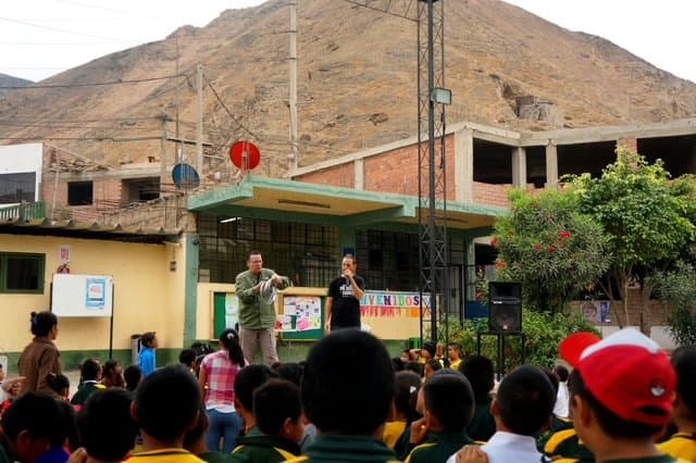 Eric Thompson captivates a crowd of enthusiastic children at what appears to be a school assembly, bringing his signature blend of comedy and magic to young audiences in this outdoor desert setting.