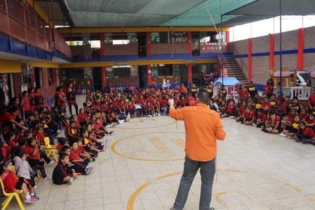 Eric Thompson captivates a massive audience of enthusiastic students gathered in a school gymnasium, showcasing his talent for connecting with young crowds during what appears to be an exciting school assembly performance.