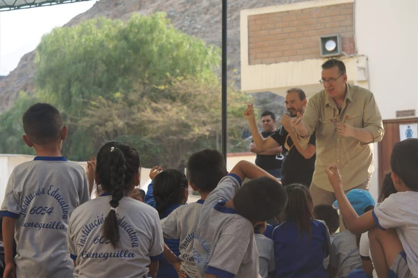 Eric Thompson captivates a group of young students during what appears to be an educational or community outreach performance, with the kids eagerly raising their hands to participate in his interactive show.