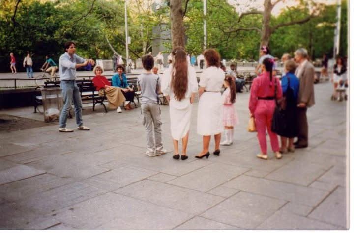 Eric Thompson draws a curious crowd in what appears to be a public square or plaza, with onlookers gathering to see what magical entertainment he has in store for them.