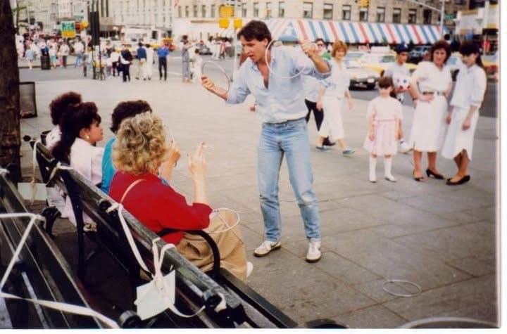 Eric Thompson captivates a street-side audience with his animated performance, drawing curious onlookers and delighting the seated spectators with his signature blend of comedy and charm.