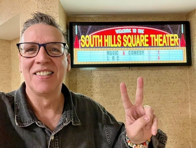Eric Thompson flashes a peace sign and his signature smile outside the South Hills Square Theater, where magic and comedy take center stage for another entertaining show.
