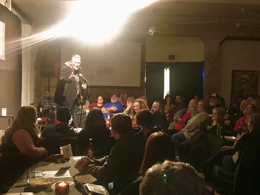Eric Thompson commands the spotlight at an intimate comedy club, working his magic on a captivated audience who can't help but lean in for every joke and trick.