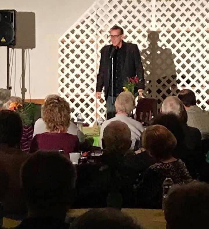 Eric Thompson commands the stage at what appears to be a church or community center event, working his magic with an intimate but engaged audience gathered before him.