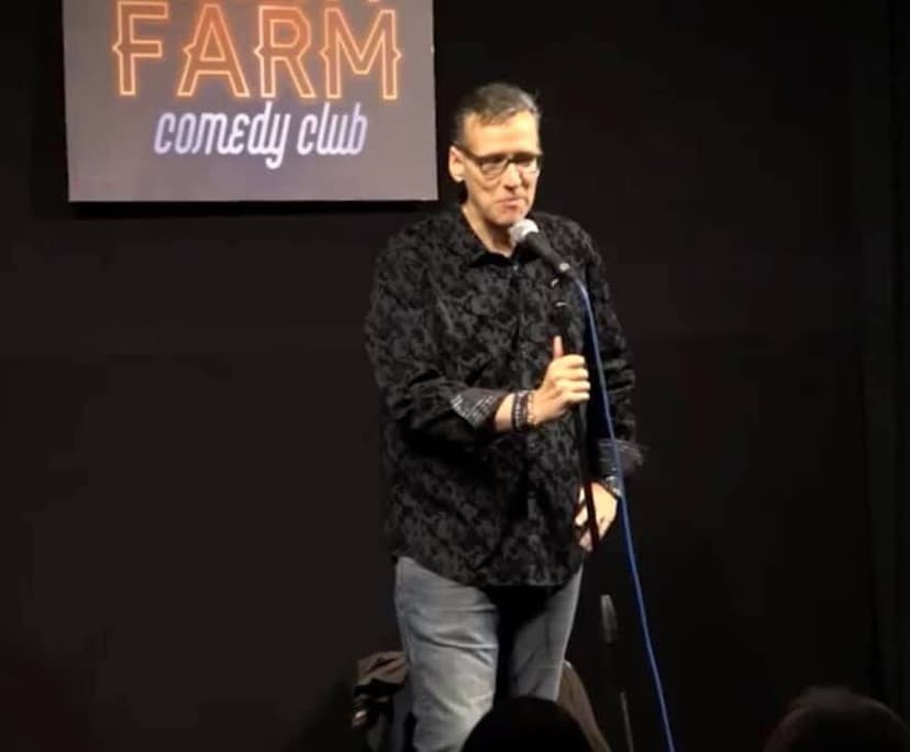 Eric Thompson takes the stage at Farm Comedy Club, commanding the microphone with his signature blend of humor and showmanship that has kept audiences laughing since the 1980s.