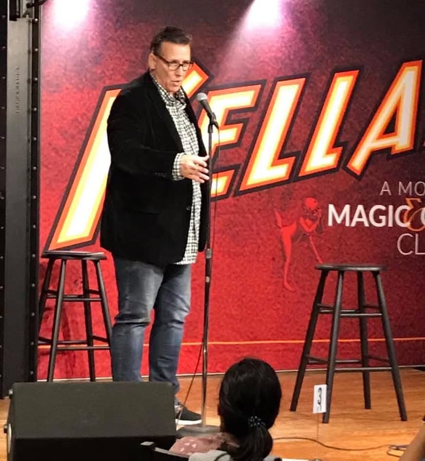 Eric Thompson commands the stage with his signature wit and charm, delivering laughs to an intimate comedy club audience from behind the microphone.
