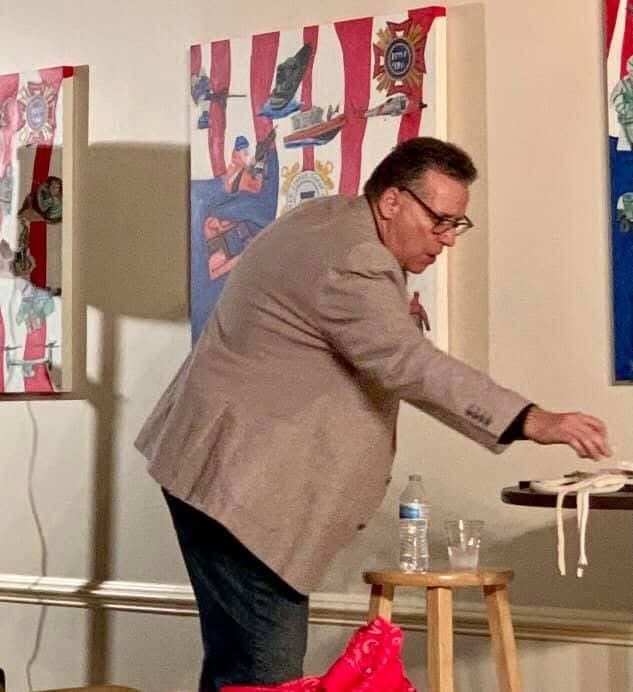 Eric Thompson demonstrates his magical prowess at what appears to be a community event, leaning in with focused concentration as he works his enchanting craft for an eager audience.