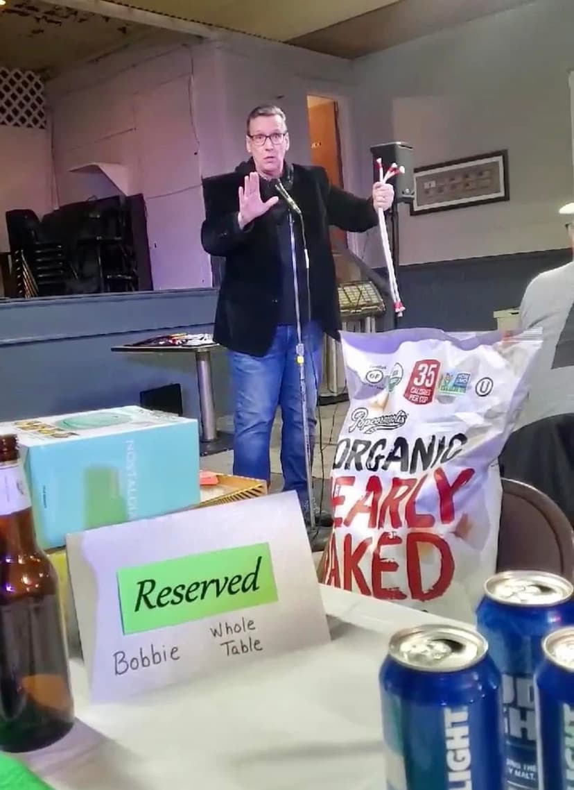 Eric Thompson brings his signature blend of comedy and magic to what appears to be a casual venue performance, complete with reserved seating for 'Bobbie' and some organic barley snacks as props - you never know what Eric will incorporate into his entertaining act!