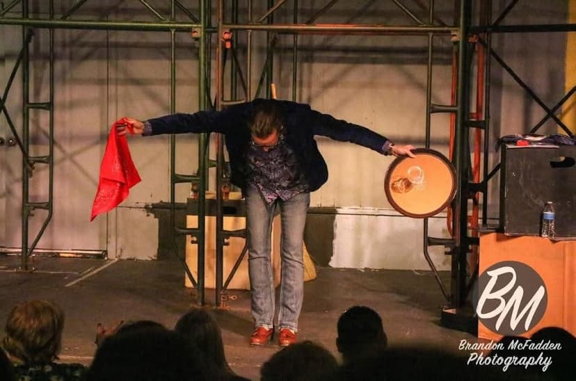 Eric Thompson captivates the audience with his signature blend of magic and comedy, dramatically wielding a red silk and brass cymbal as part of an elaborate theatrical routine that keeps the crowd on the edge of their seats.