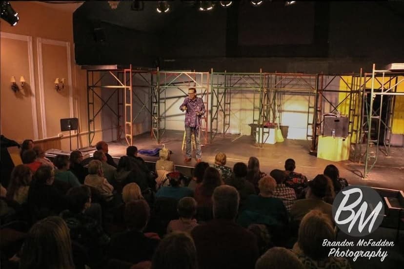 Eric Thompson commands the stage at an intimate theater performance, working his magic in front of a captivated audience surrounded by an impressive scaffolding set design.