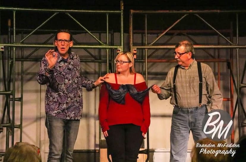 Eric Thompson takes his final bow with fellow performers during what appears to be a theater production, sharing warm smiles and linked arms as they acknowledge the audience's applause.