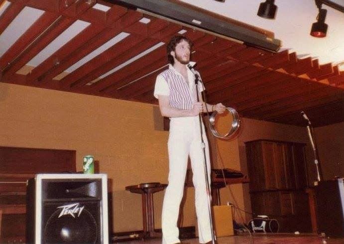 Eric Thompson commands the stage with his signature blend of comedy and magic, working his charm on the audience from behind the microphone at what appears to be an intimate venue performance.