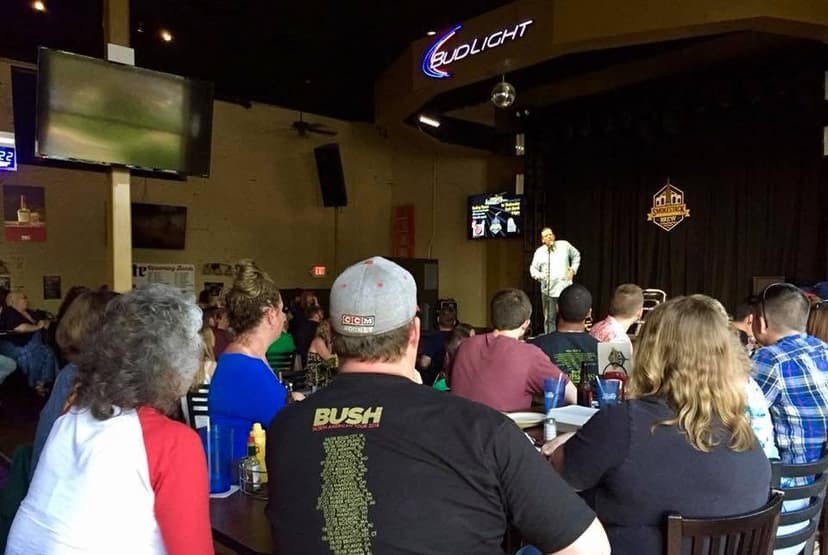 Eric Thompson commands the stage at a lively comedy club performance, entertaining a packed house of eager fans who hang on his every word.